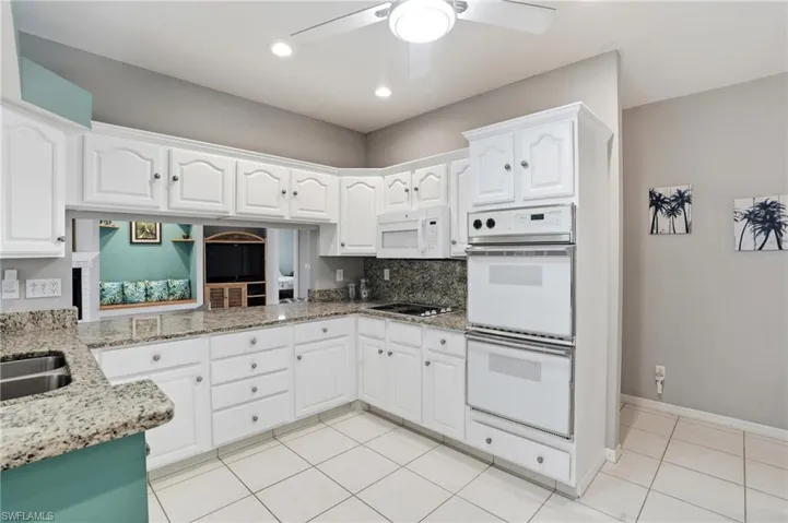 Kitchen with light stone countertops, white appliances, white cabinetry, a ceiling fan, and recessed lighting