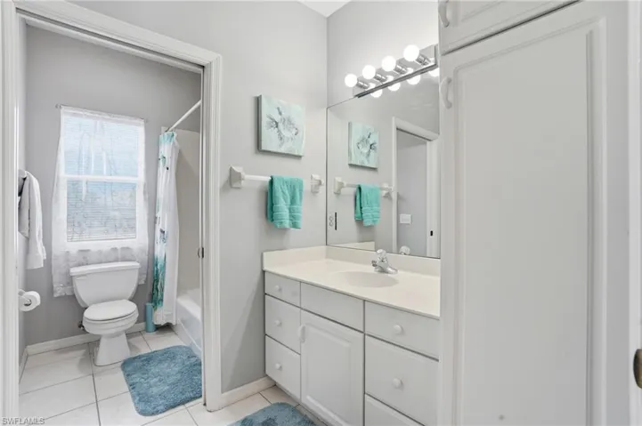 Bathroom with vanity, shower / bath combo with shower curtain, and light tile patterned floors