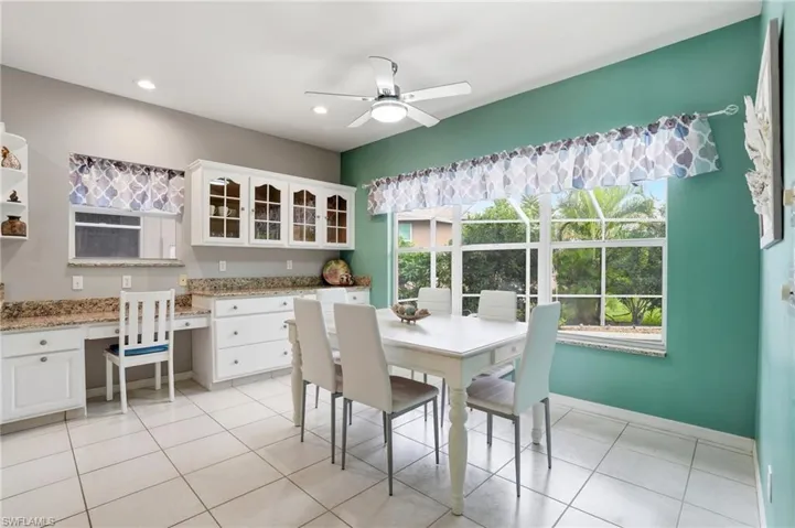 Dining room with ceiling fan, built in study area, and light tile patterned floors