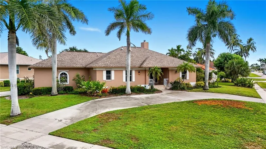 Ranch-style home featuring a front yard, stucco siding, curved driveway, and a chimney