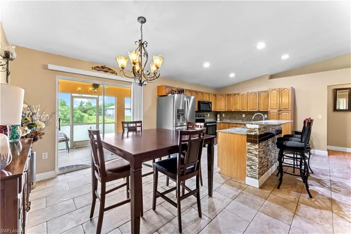 Dining room featuring sink, an inviting chandelier, light tile patterned floors, and vaulted ceiling