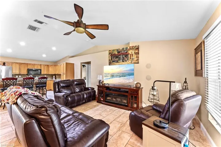 Tiled living room with lofted ceiling, ceiling fan, and plenty of natural light