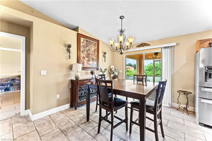 Tiled dining area featuring lofted ceiling and a chandelier