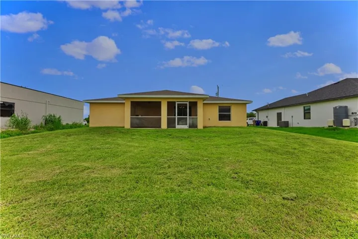 Rear view of house featuring a sunroom and a yard