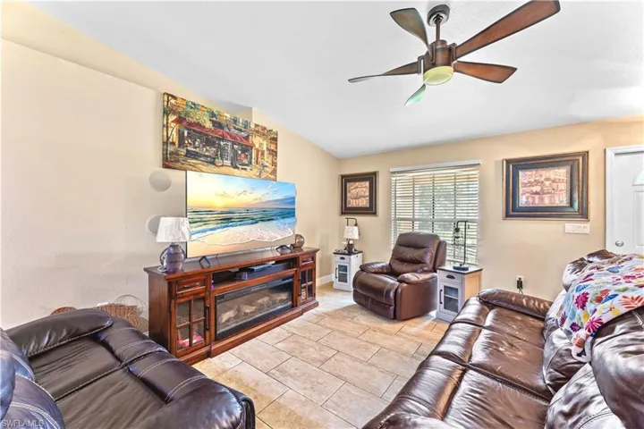 Tiled living room with ceiling fan and vaulted ceiling