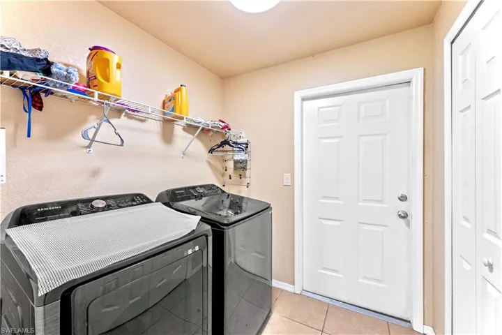 Laundry room with light tile patterned flooring and washer and clothes dryer