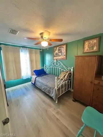 Bedroom with a textured ceiling, wood finished floors, and ceiling fan