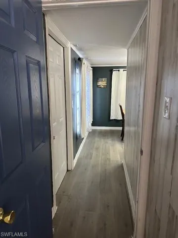 Corridor featuring wood finished floors, baseboards, and crown molding