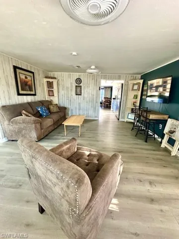 Living room featuring wood finished floors, a textured ceiling, and wooden walls