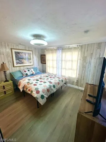 Bedroom featuring wood finished floors, a textured ceiling, and wood walls