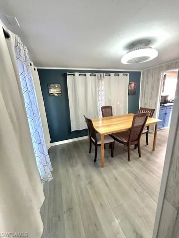 Dining area with light wood-type flooring, a textured ceiling, and baseboards