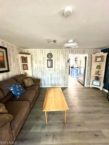 Living area with wood finished floors, baseboards, wood walls, and a textured ceiling