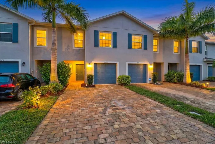 View of front of house with stucco siding and decorative driveway