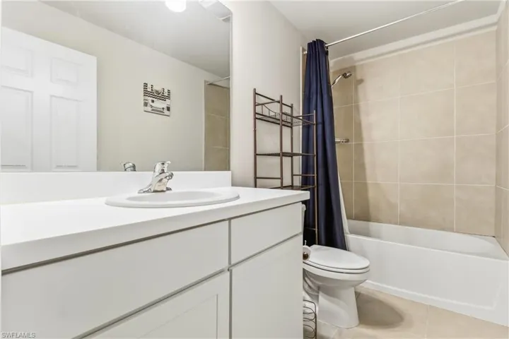 Bathroom with shower / tub combo with curtain, vanity, and light tile patterned floors
