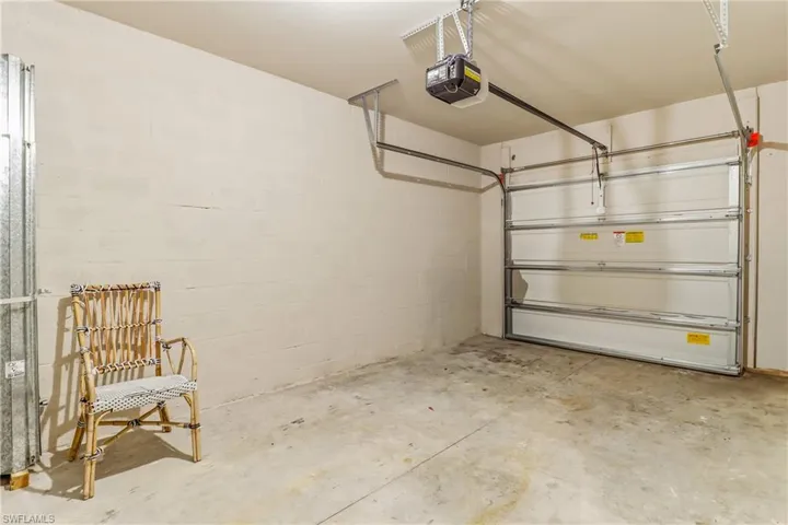 Garage featuring a garage door opener and concrete block wall