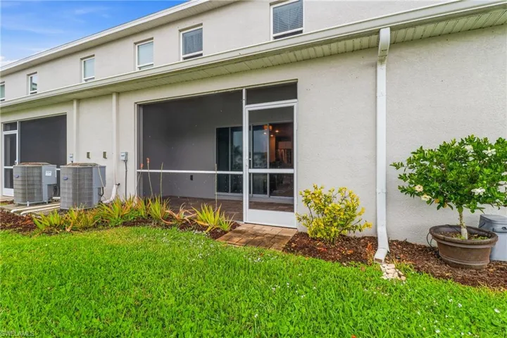Rear view of property featuring stucco siding, a yard, and a sunroom