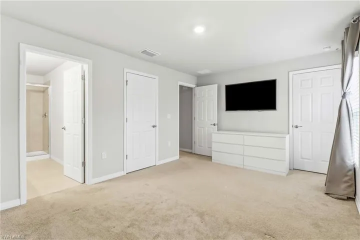 Unfurnished bedroom with light colored carpet and connected bathroom