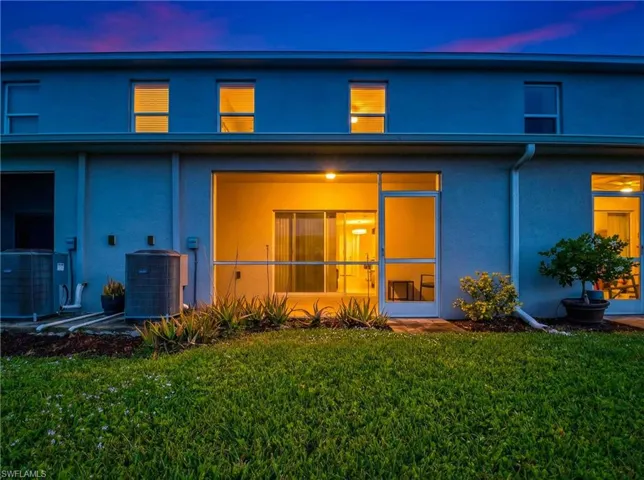 Back of house featuring stucco siding and a lawn