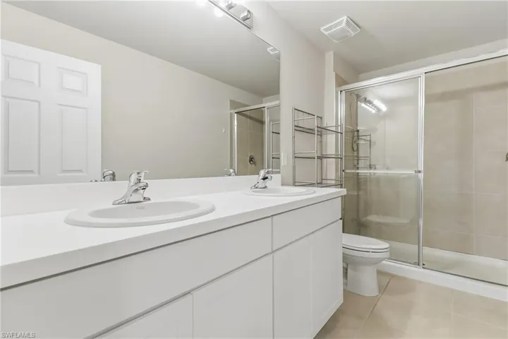 Full bathroom with double vanity, a stall shower, and light tile patterned floors