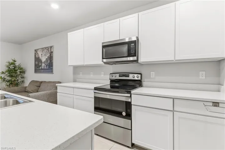 Kitchen featuring stainless steel appliances, white cabinets, open floor plan, recessed lighting, and light tile patterned floors