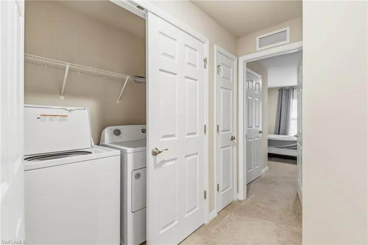 Laundry room with light colored carpet and washing machine and dryer