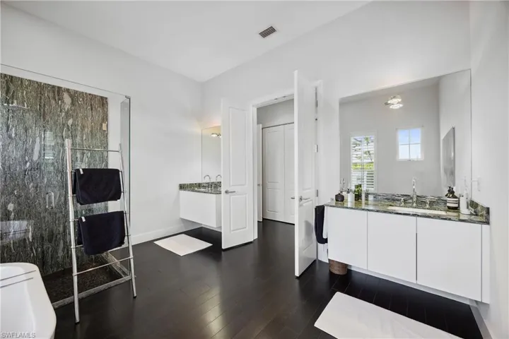 Bathroom with two vanities, a shower stall, and dark wood finished floors