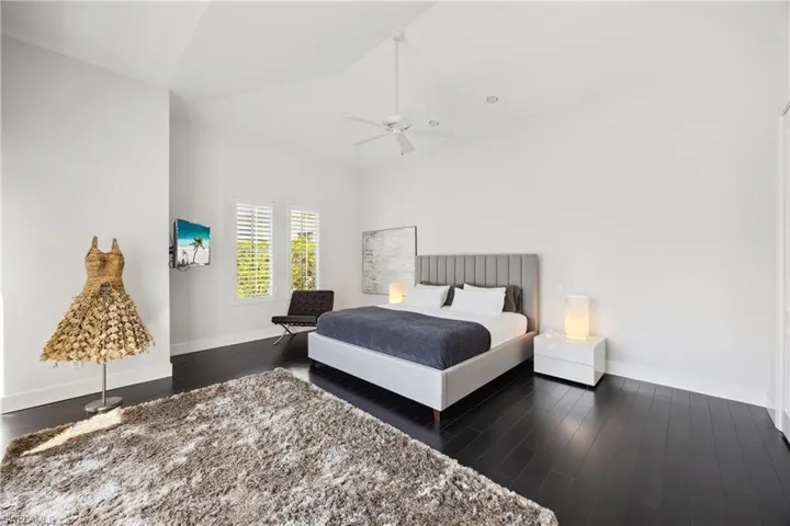 Bedroom with dark wood-style flooring, vaulted ceiling, and ceiling fan