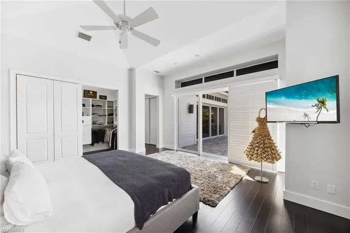 Bedroom with a closet, dark wood-style floors, ceiling fan, and access to exterior