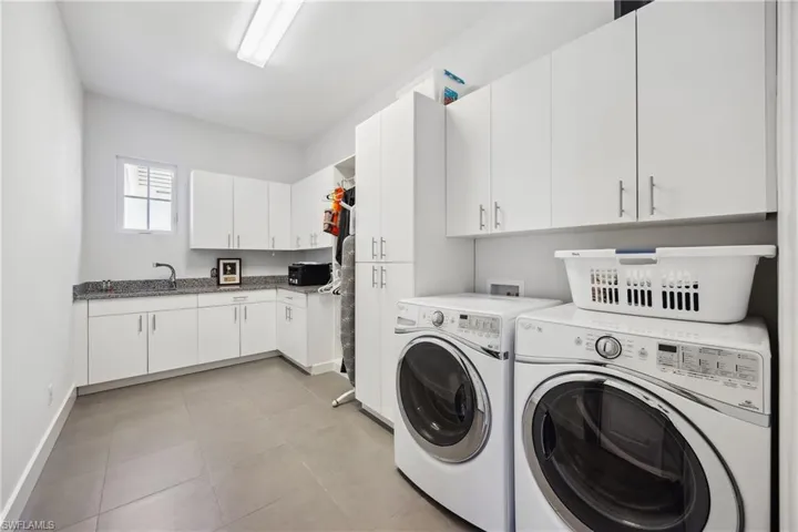 Laundry area with cabinet space, washer and clothes dryer, and light tile patterned floors