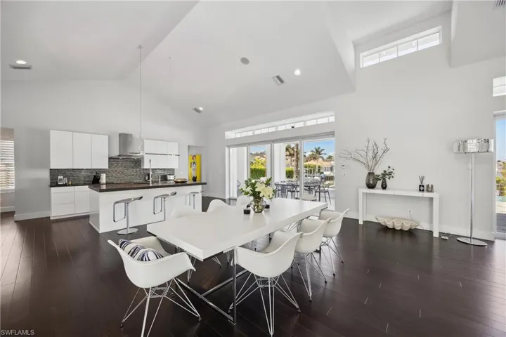 Dining room with high vaulted ceiling and dark wood-style floors