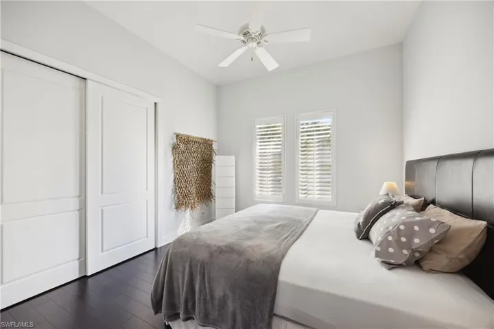 Bedroom with dark wood-style flooring, ceiling fan, and a closet