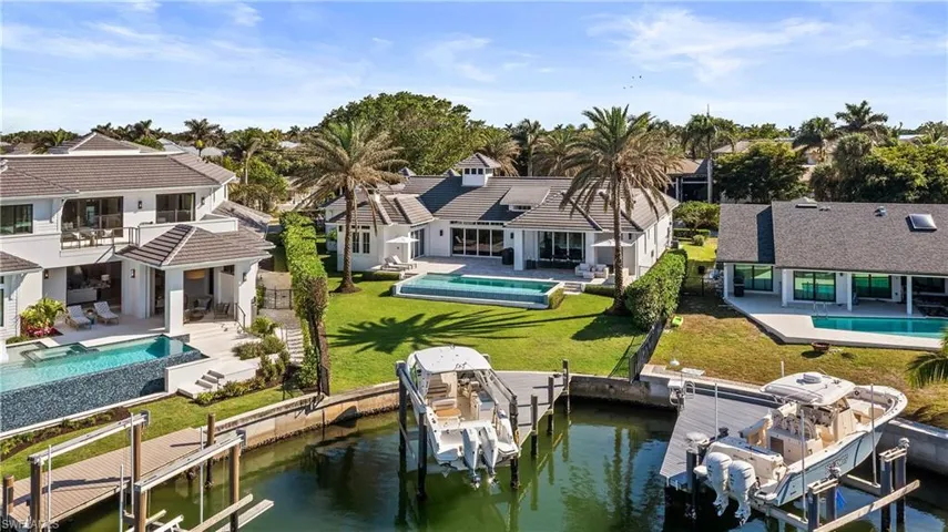 Rear view of house featuring an outdoor pool, a patio, boat lift, and a water view