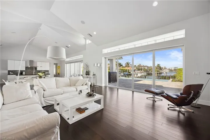 Living area featuring high vaulted ceiling, a water view, dark wood finished floors, and recessed lighting