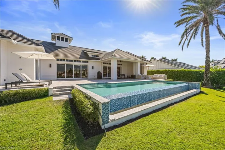 View of swimming pool with ceiling fan, a patio area, and a lawn
