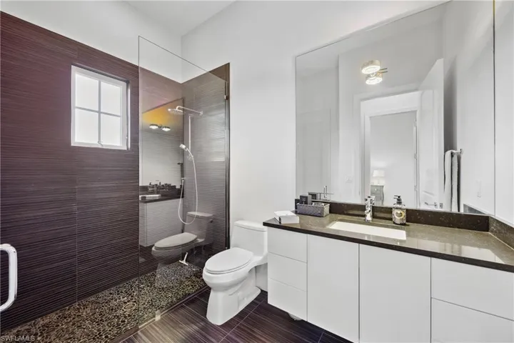 Full bathroom featuring a walk in shower, vanity, and dark tile patterned floors