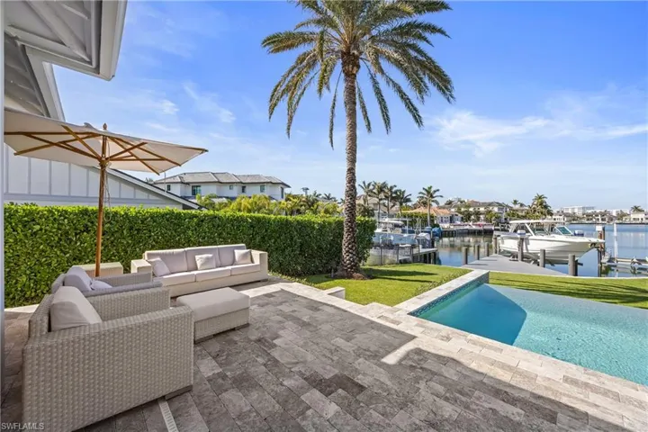 Swimming pool featuring a water view, a patio area, an outdoor living space, boat lift, and a yard