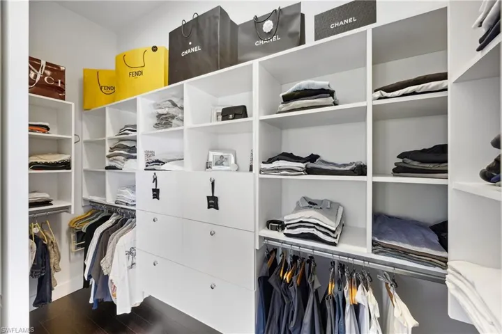 Walk in closet with dark wood-type flooring