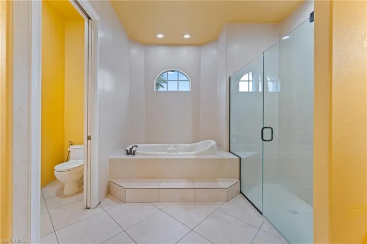 Bathroom featuring toilet, tile patterned floors, and shower with separate bathtub