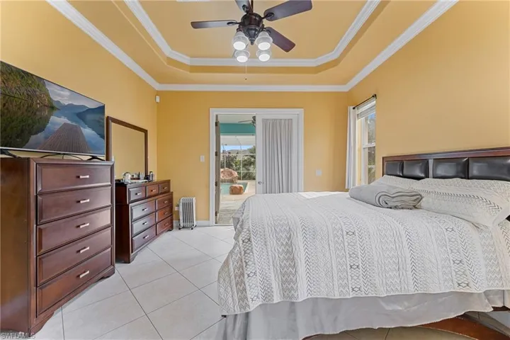 Bedroom featuring light tile patterned floors, ceiling fan, a raised ceiling, access to exterior, and radiator