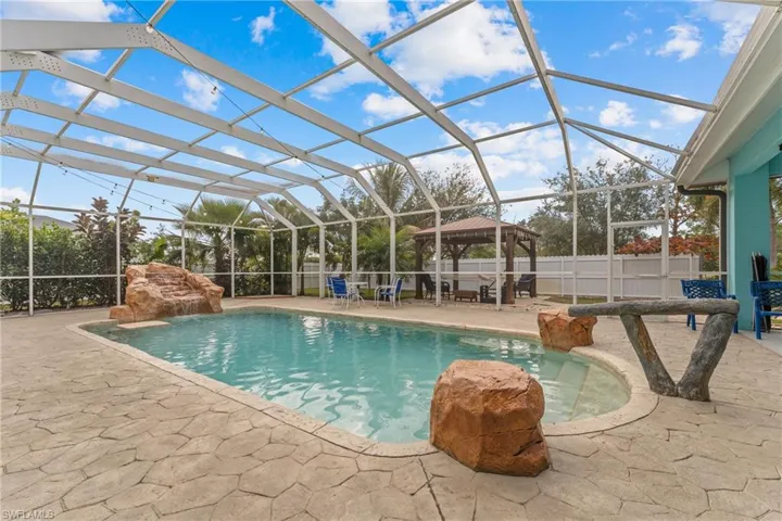View of swimming pool featuring a lanai, pool water feature, a patio area, and a gazebo