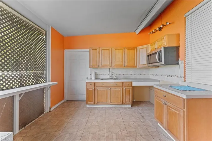 Kitchen with a wealth of natural light, decorative backsplash, light brown cabinets, and sink