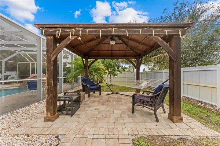 View of patio with a fenced in pool, glass enclosure, and a gazebo