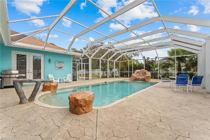 View of pool with glass enclosure, a patio area, and a grill