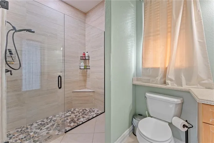 Bathroom with tile patterned floors, toilet, and walk in shower