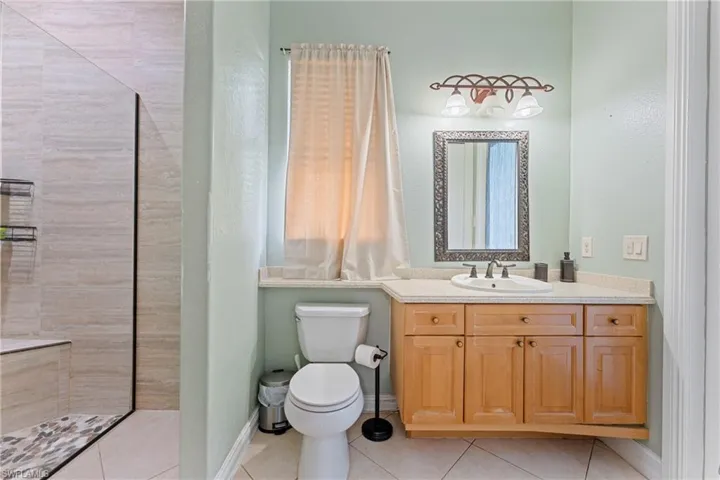 Bathroom with toilet, tile patterned floors, and vanity