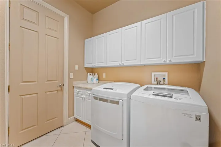 Laundry room featuring cabinets, washer and clothes dryer, and light tile patterned flooring