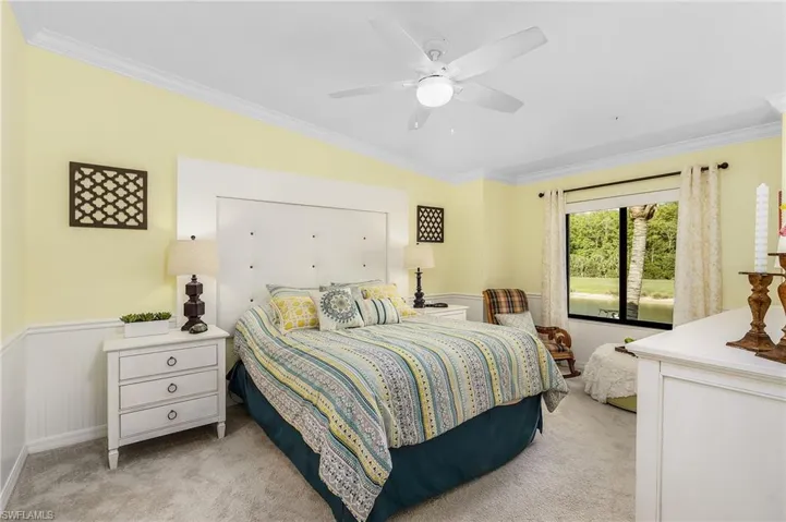 Bedroom with ornamental molding, light carpet, ceiling fan, and a wainscoted wall