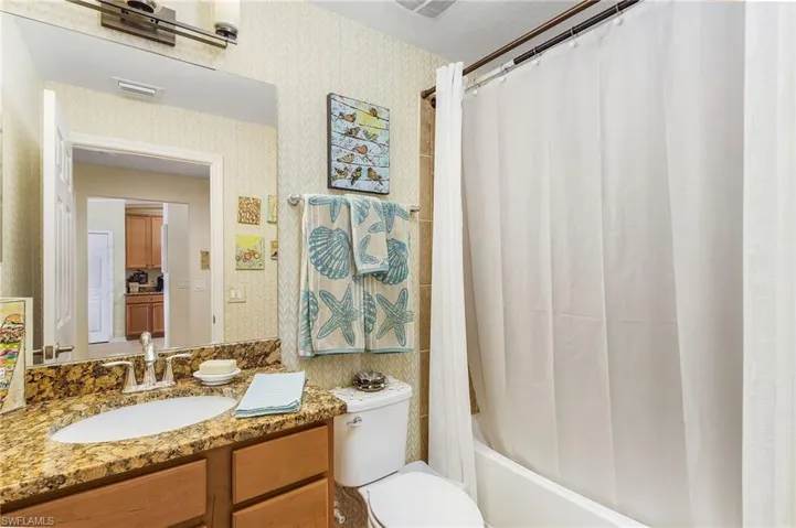 Full bathroom with vanity, shower / bath combo, and wallpapered walls