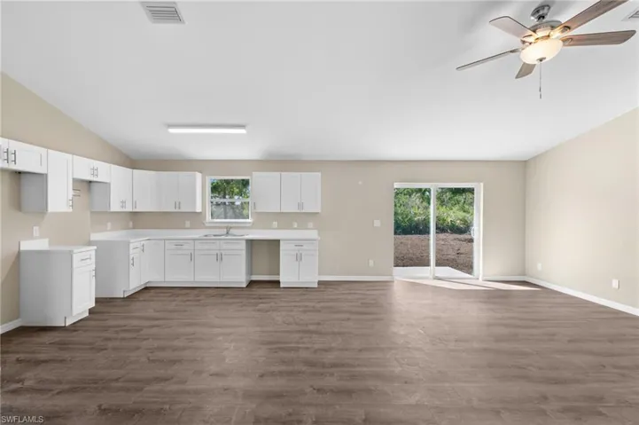 Kitchen with white cabinetry, sink, vaulted ceiling, and dark hardwood / wood-style flooring