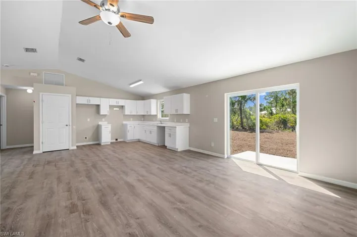 Unfurnished living room featuring sink, ceiling fan, light hardwood / wood-style flooring, and vaulted ceiling